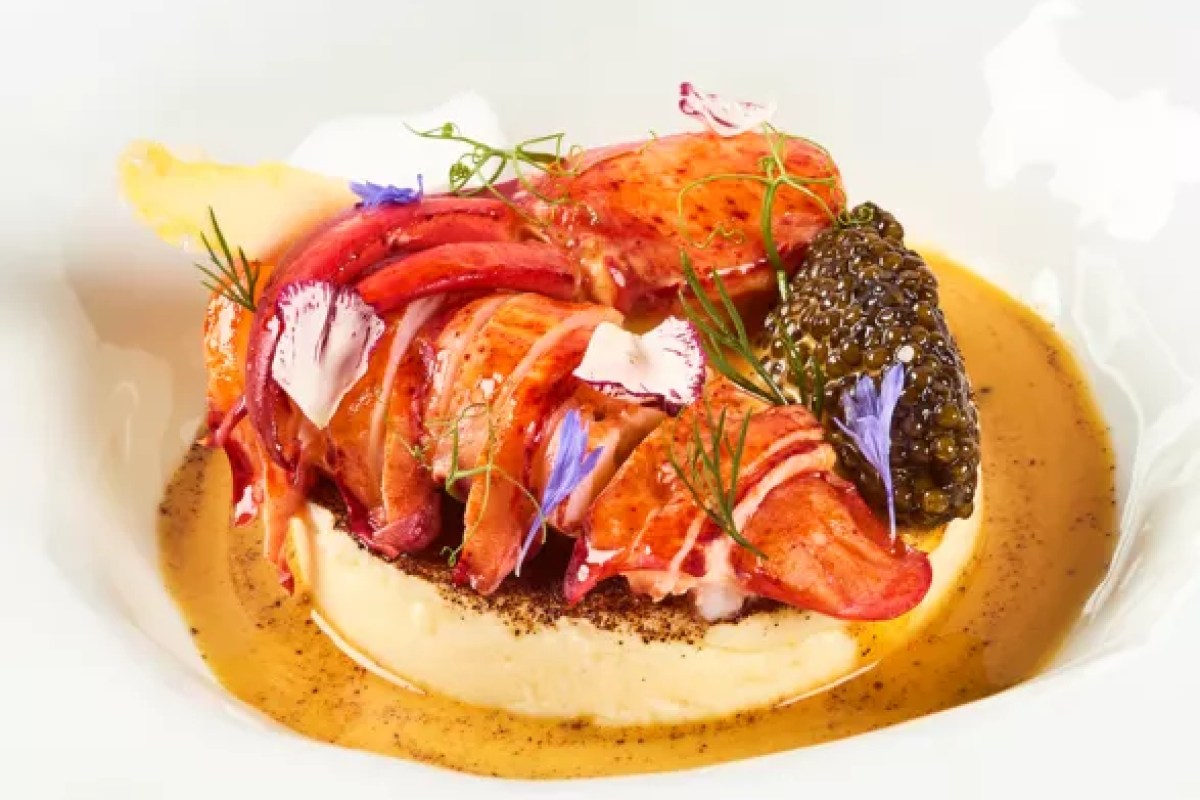 Plated lobster dish with caviar and edible flowers in a rich sauce