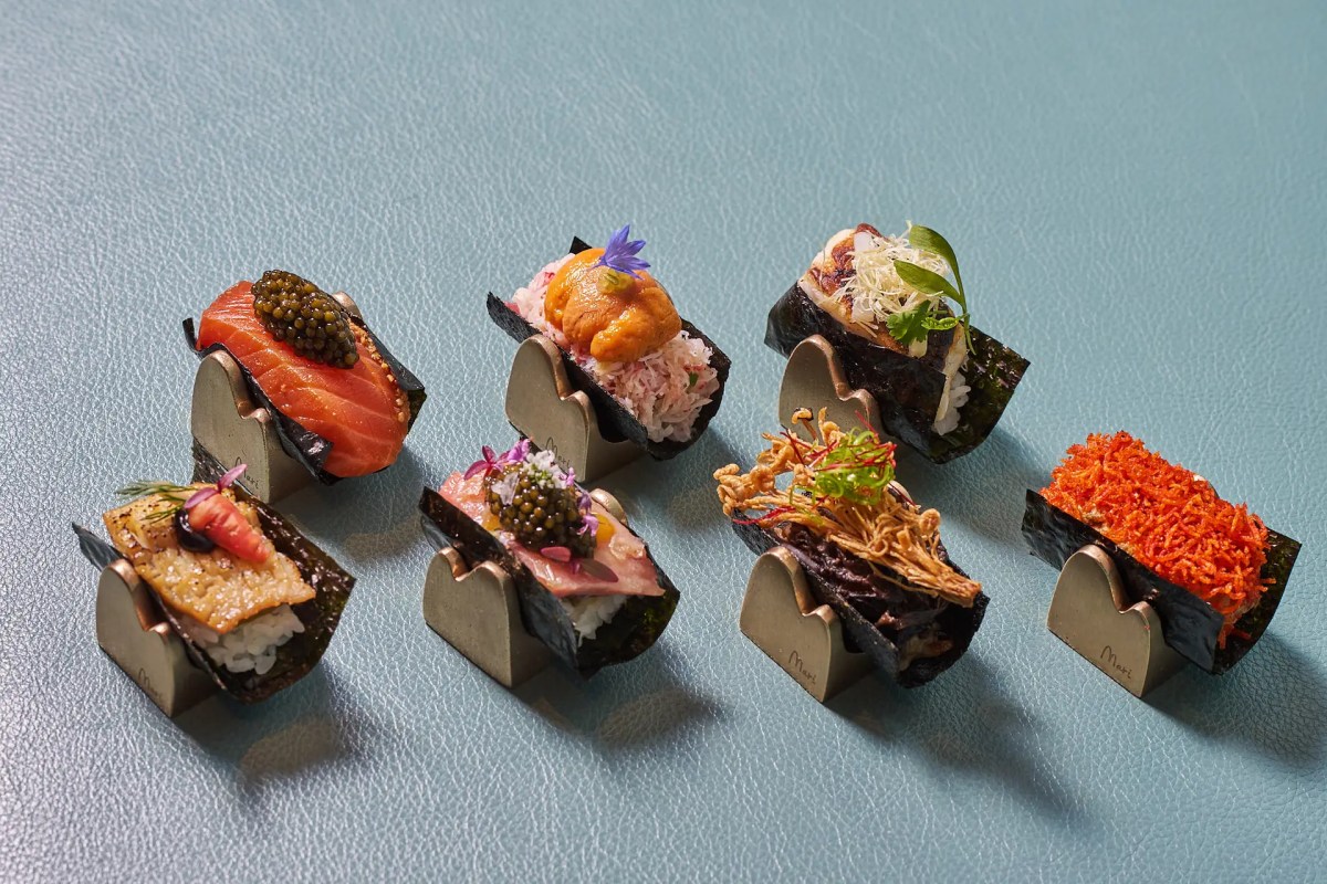 Six pieces of nigiri sushi with various toppings on nori stands, blue leather background