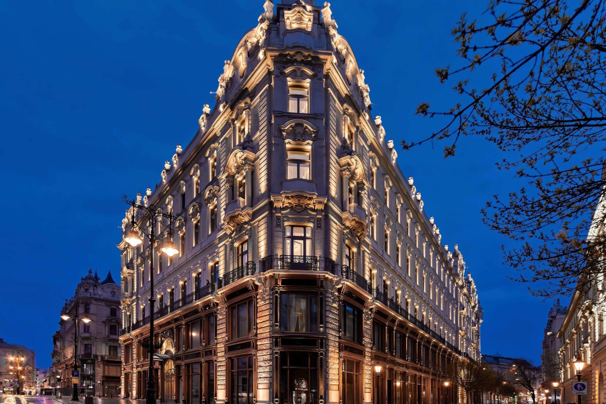 Ornate historic façade of Matild Palace illuminated at dusk on a Budapest street corner