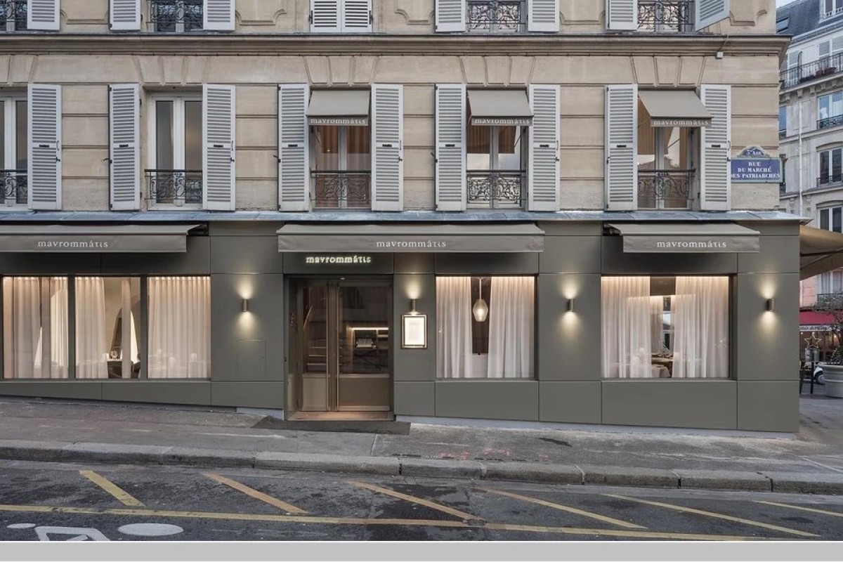 Restaurant exterior with grey facade, awnings reading 'mavrommátis', shuttered windows above, on a Paris street corner