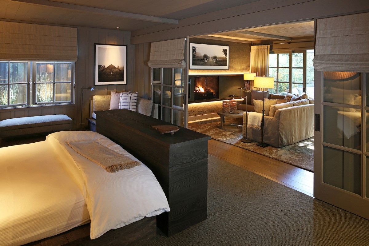 Spacious guest suite with bed, fireplace lounge area, and warm wood tones