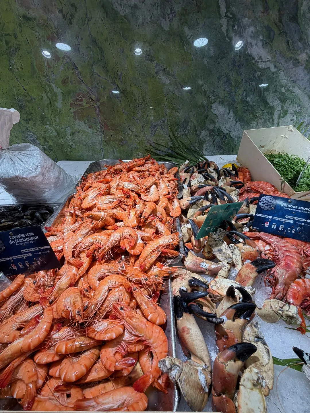 Pink prawns and crab claws piled on crushed ice with handwritten labels at La Sirène, the fishmonger next to Mersea