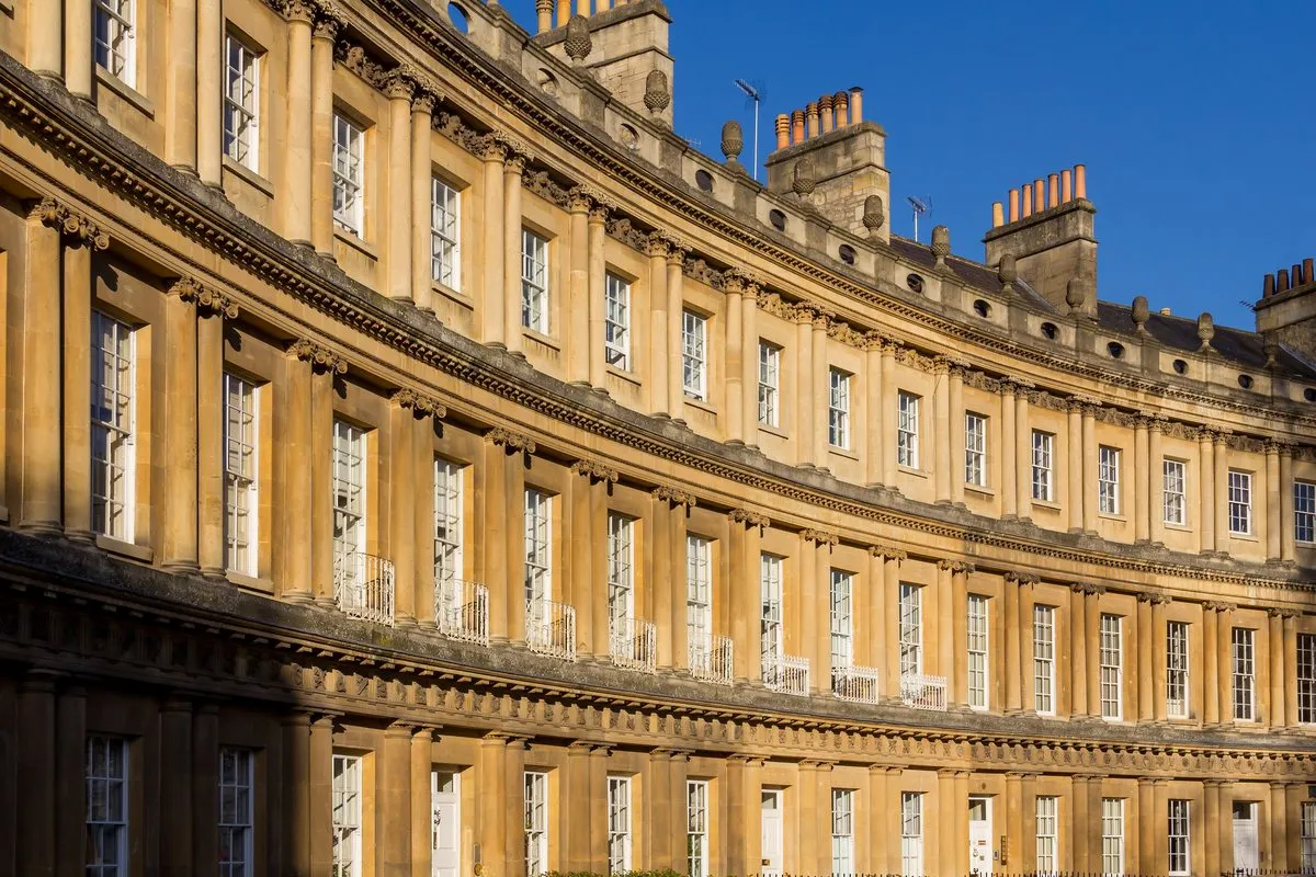 The curving Georgian façade of the Royal Crescent in Bath in golden evening light