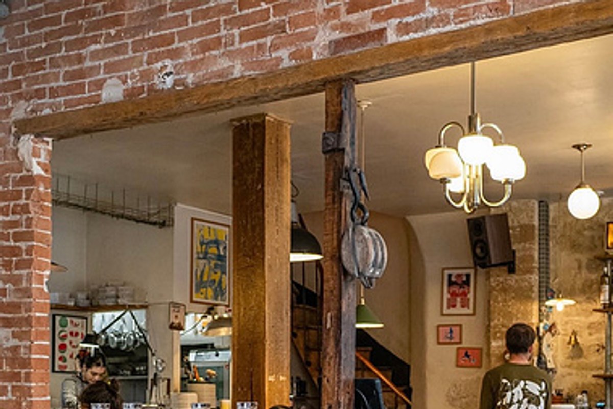Interior dining area with exposed brick wall, wooden beams, pendant lights and art on walls