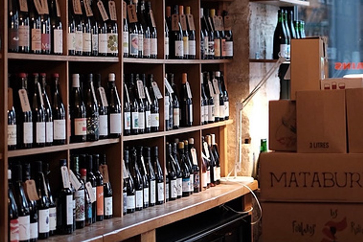 Wine bottles on wooden shelves, bar/cellar area with cardboard delivery boxes