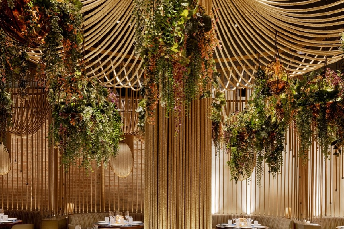 Elegant dining room with decorative rope ceiling and hanging greenery installations above table settings
