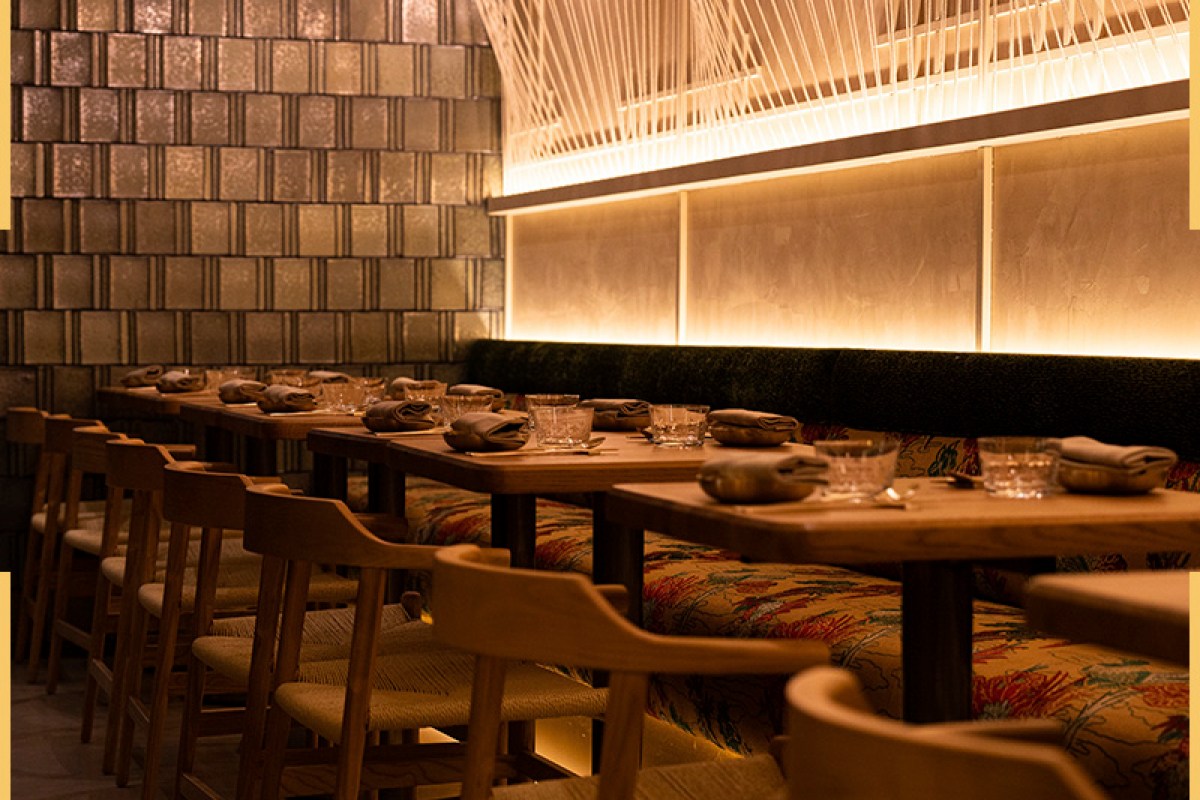 Dining room with banquette seating, woven light fixture, and set wooden tables at Mojju restaurant