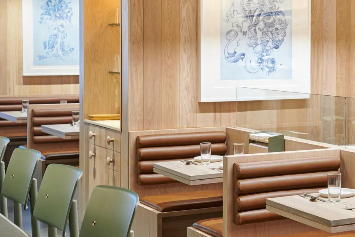 Modern restaurant dining room with wood paneling, leather booths, and framed blue artwork
