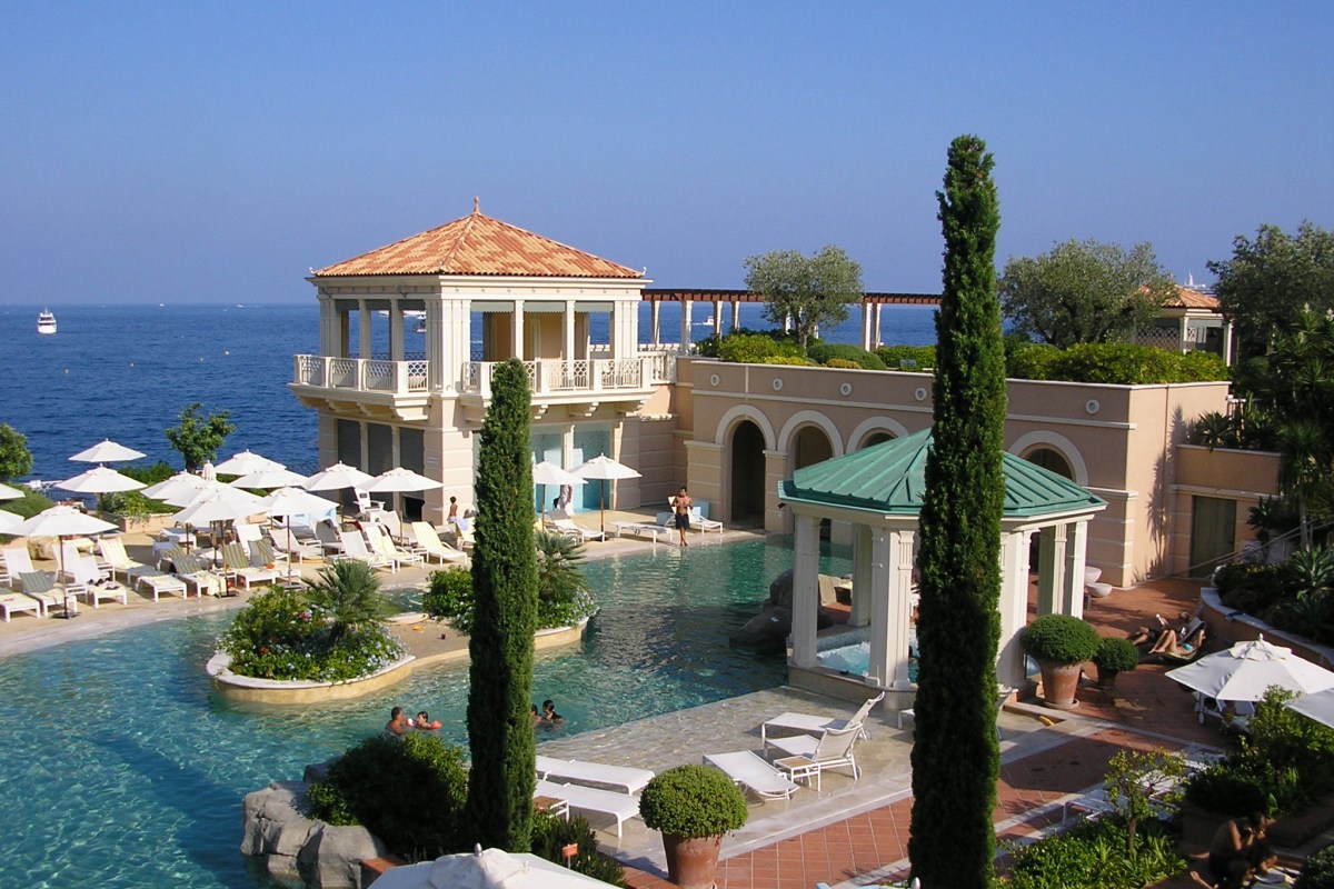 Hotel pool area with lagoon-style pool, pavilions and sea view, guests relaxing