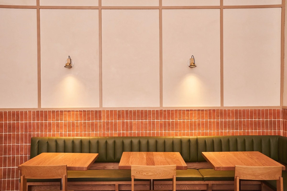 Dining room wall with terracotta tile wainscoting, wood tables and chairs, and two wall sconces