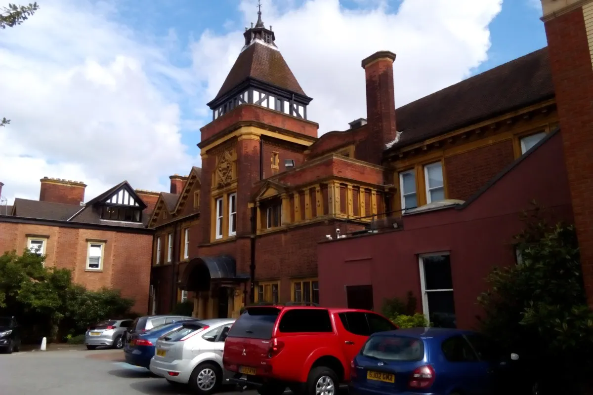 Red-brick Moor Hall hotel exterior with turret, chimneys and car park in foreground