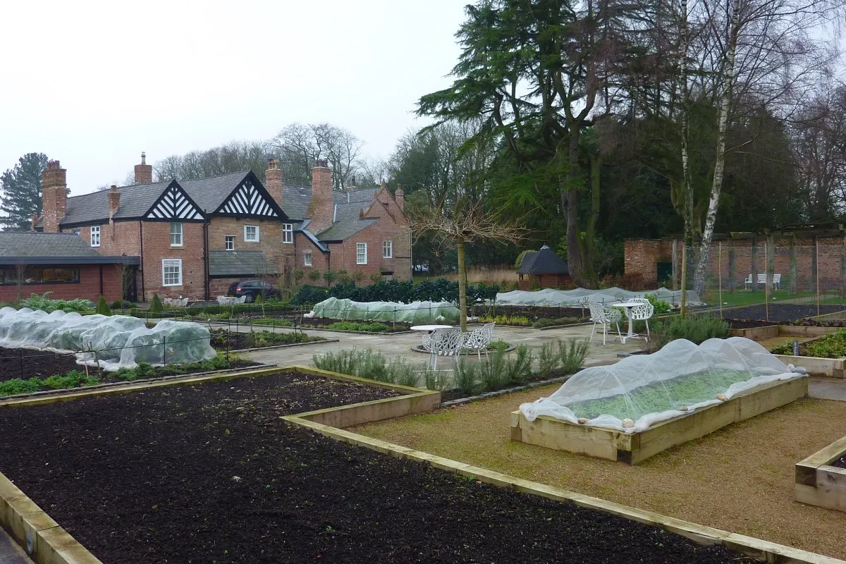 Hotel's walled kitchen garden with raised beds, seating and Moor Hall building behind