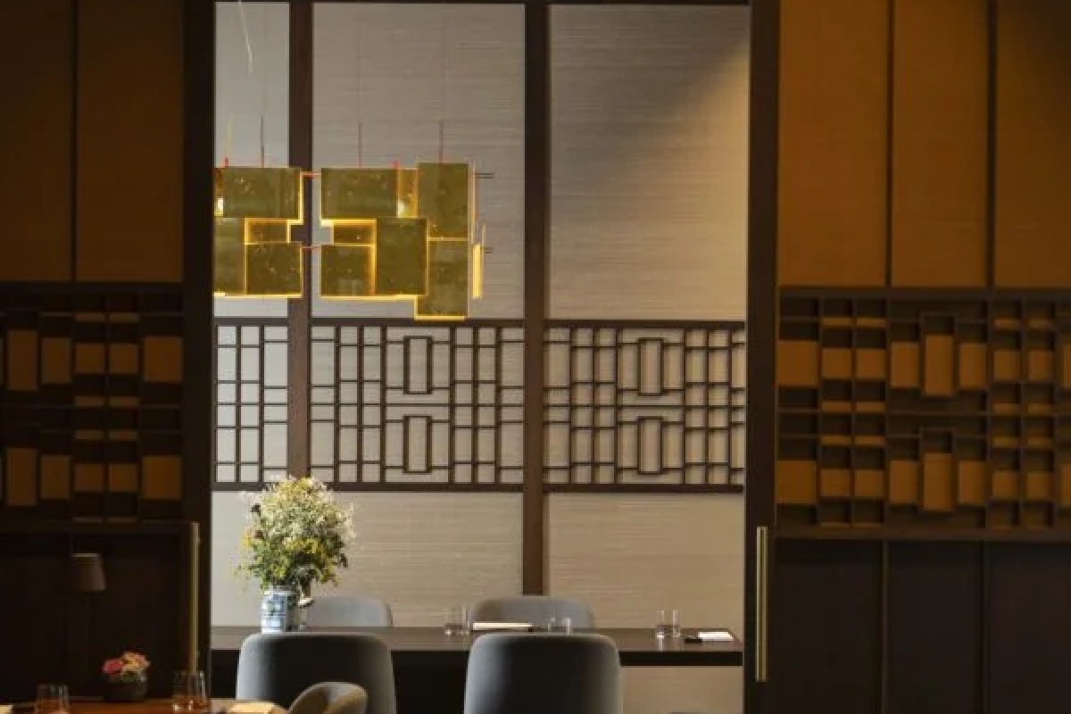 Elegant dining room with Asian-inspired wood screens, pendant light fixture, and table with flowers, seen through a doorway