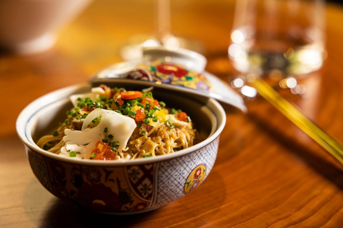 Bowl of noodles topped with seafood, herbs and fish roe in a decorated porcelain bowl