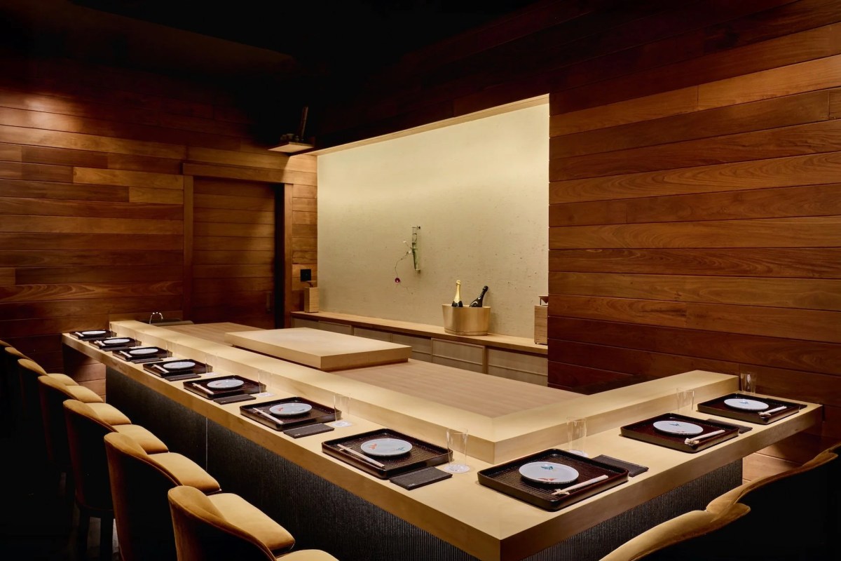 Wood-paneled dining counter with place settings, trays, chopsticks and chairs at Muku restaurant
