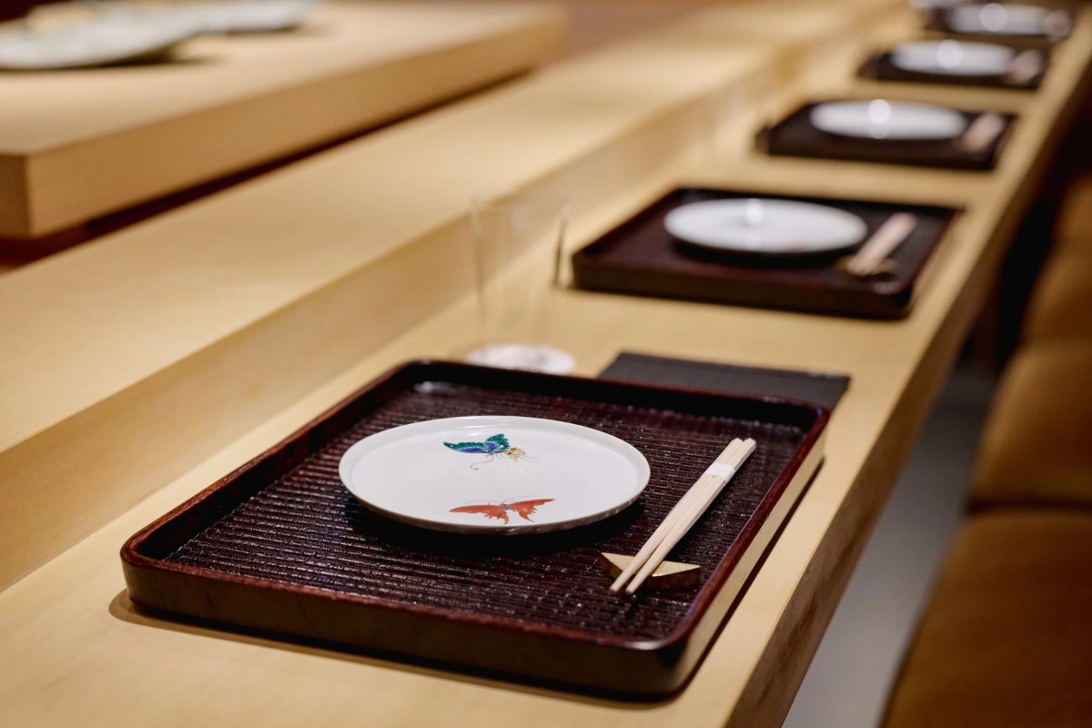 Close-up of a table setting with a decorative plate, chopsticks on a dark tray at the counter