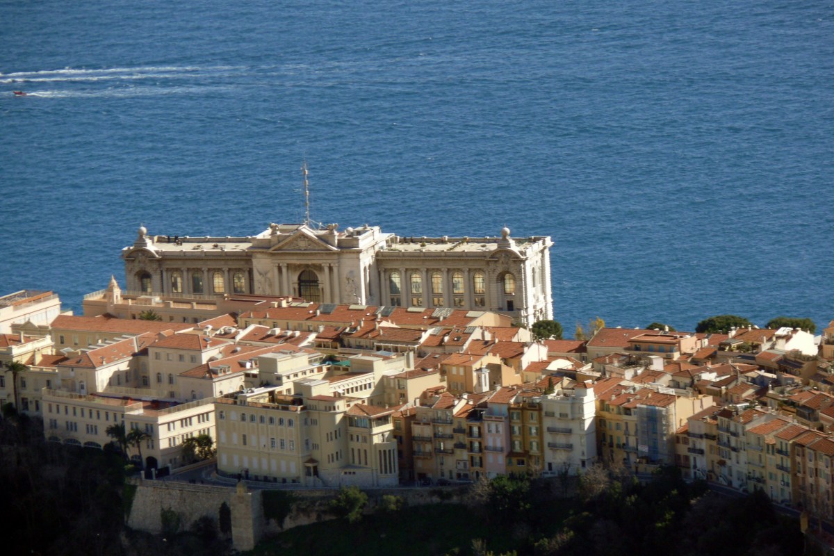 Distant aerial view of Monaco-Ville with the Oceanographic Museum's facade overlooking the sea.