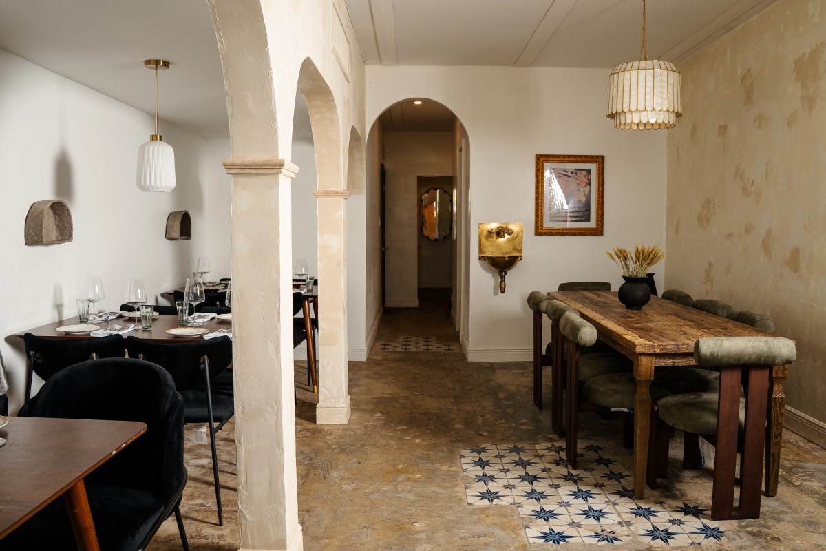 Dining room with arched doorways, wooden tables, patterned floor tiles, and warm lighting