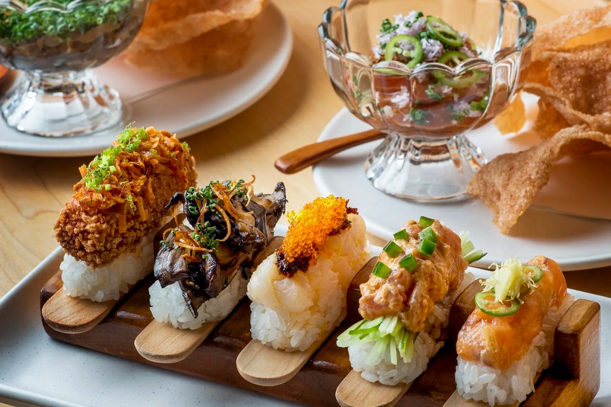 Assortment of specialty sushi pieces topped with crispy and glazed garnishes on a wooden board