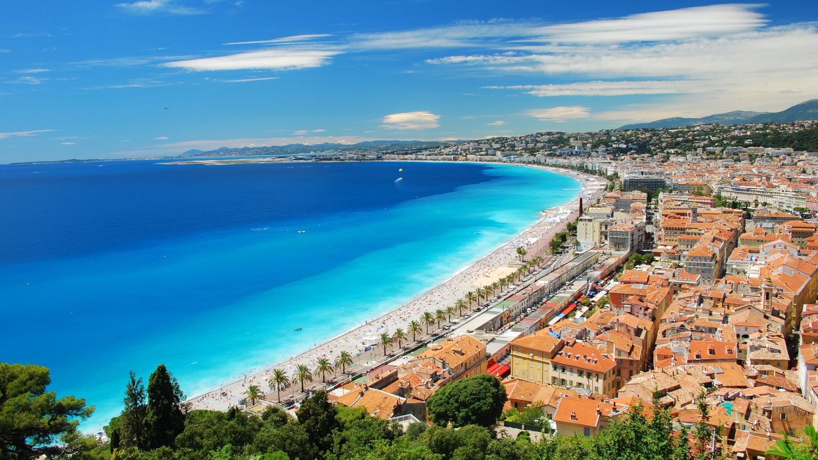 The Baie des Anges in Nice, the pebble beach and the Promenade des Anglais curving along the turquoise sea below the rooftops