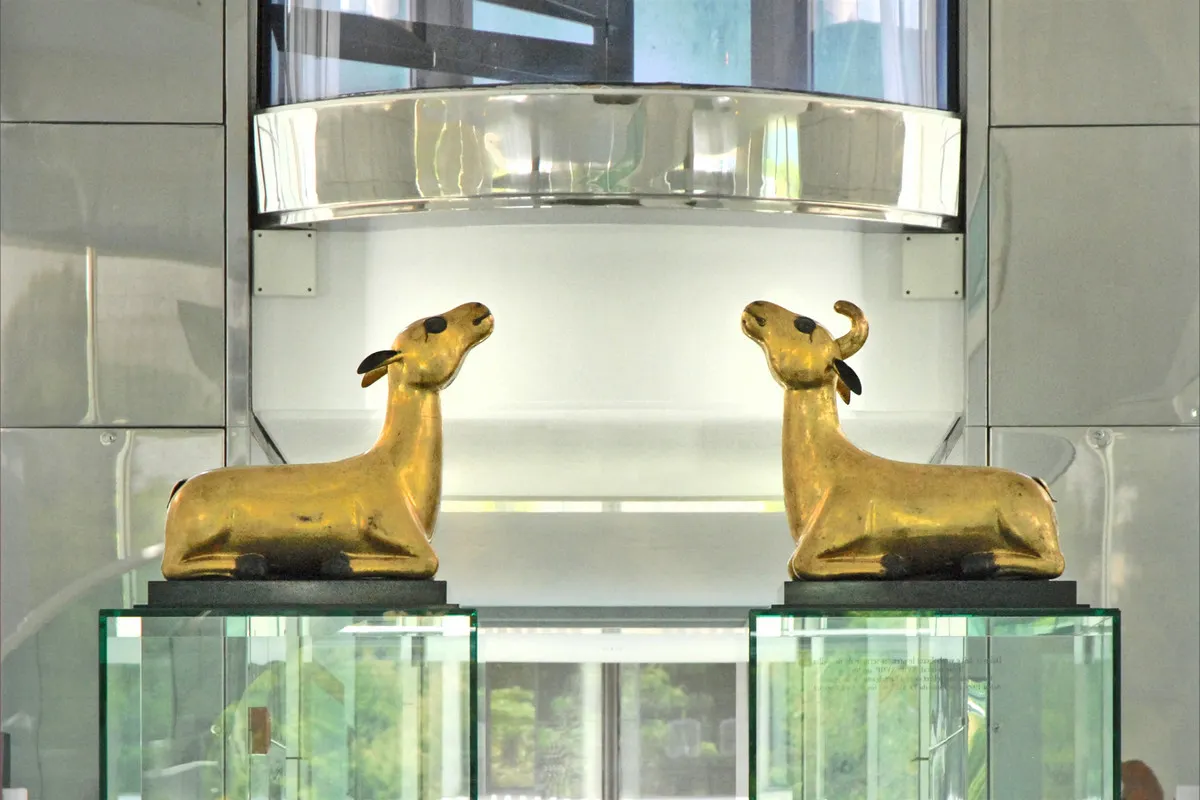 A pair of gilded deer facing each other on glass plinths in the white marble rotunda of the Musée des Arts Asiatiques in Nice