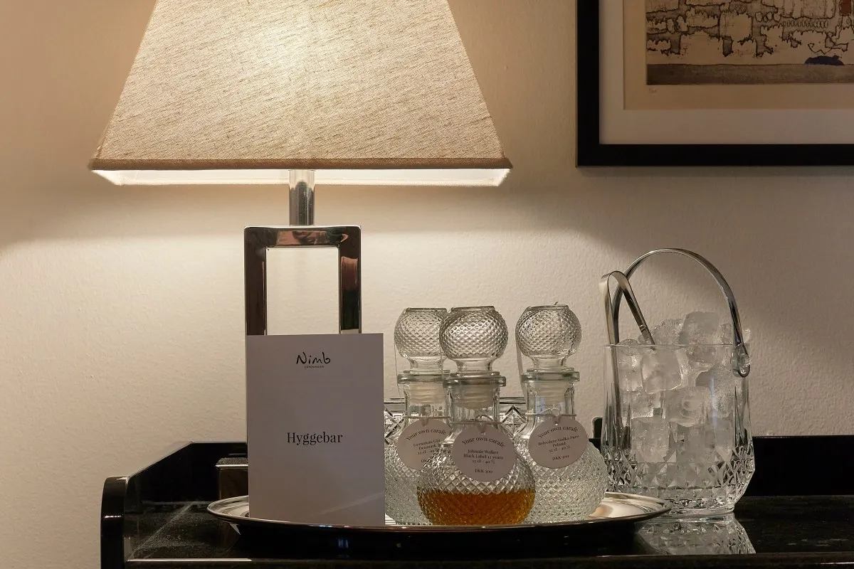 Nimb branded 'Hyggebar' tray with crystal decanters, ice bucket and lamp in a cozy hotel space