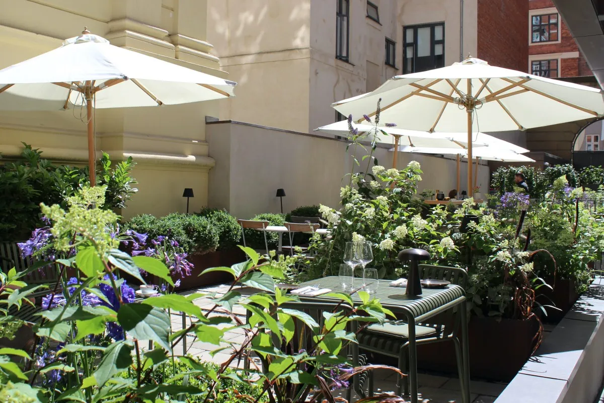 Outdoor terrace garden with umbrellas, flowers and dining table at the hotel