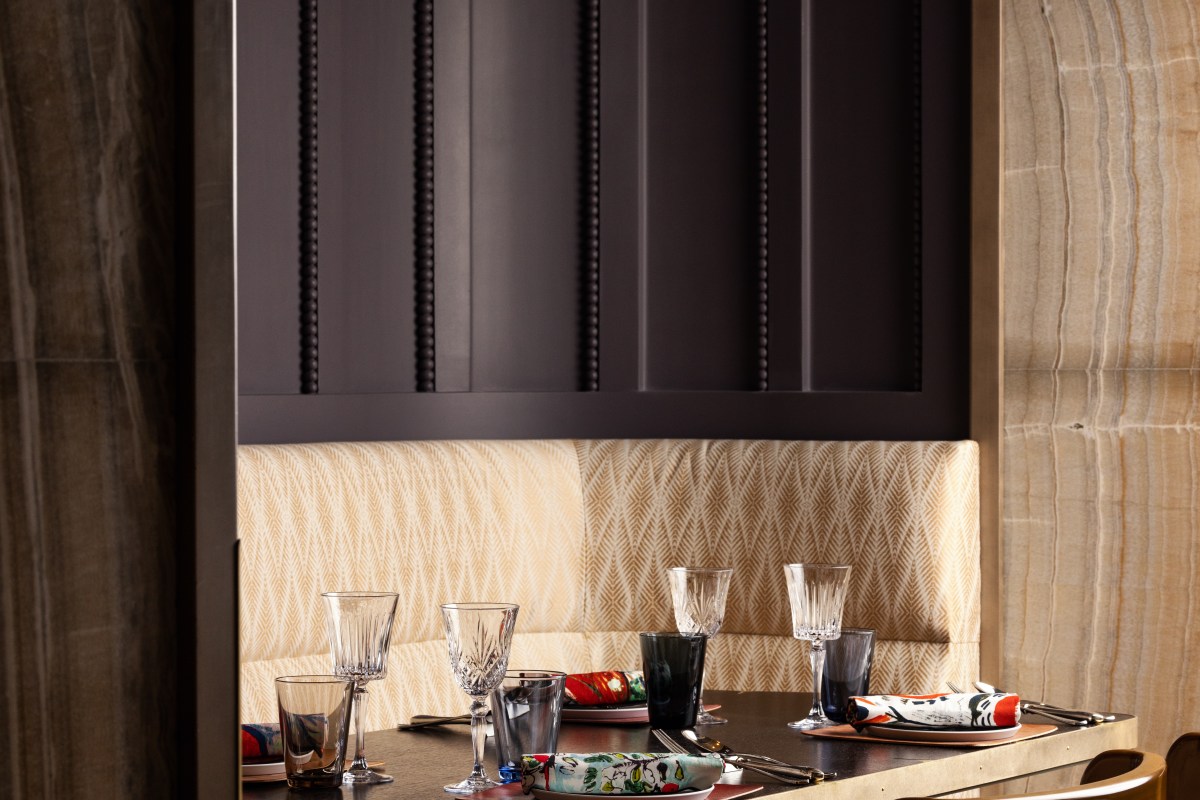 Dining room table set with crystal glassware, patterned banquette seating and dark wood paneling
