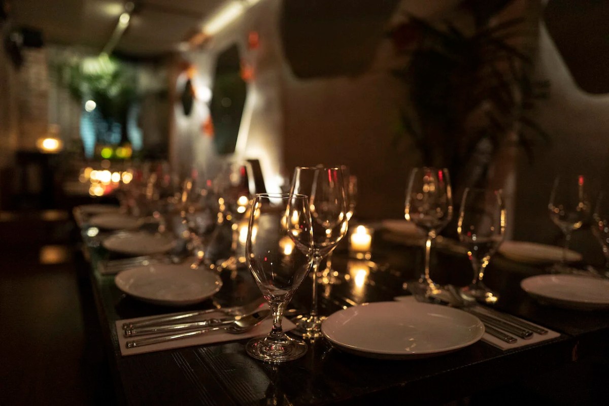 Elegant candlelit table setting with wine glasses and plates in Noreetuh's dining room