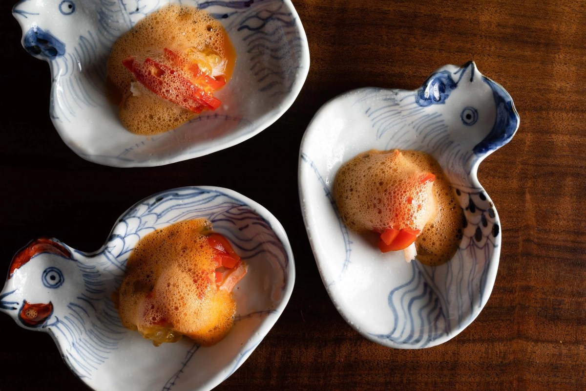 Overhead shot of bite-sized dishes with foam and chili on bird-shaped ceramic plates