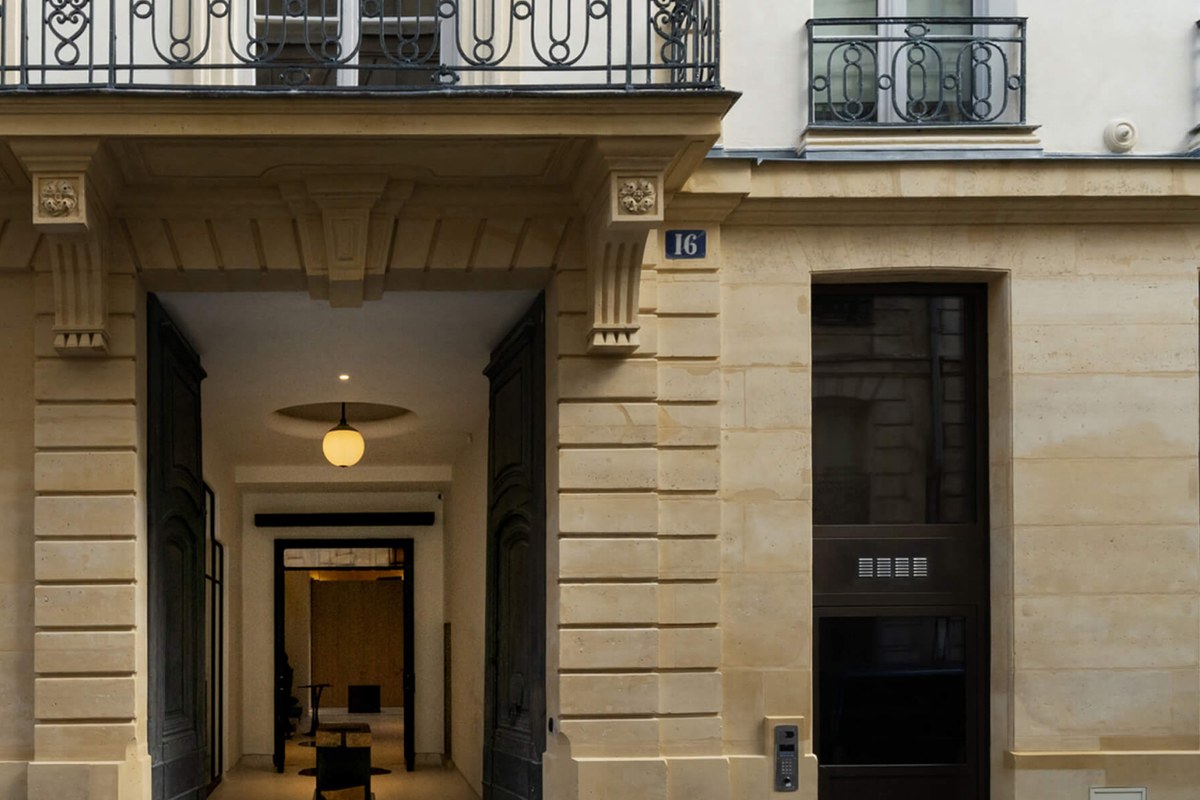 Stone building entrance with arched passageway, wrought-iron balconies, and address number 16 in Paris.