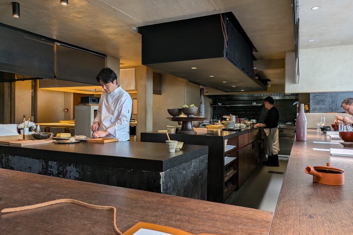 Open kitchen counter at Ogata restaurant with chefs preparing dishes behind a dark stone counter