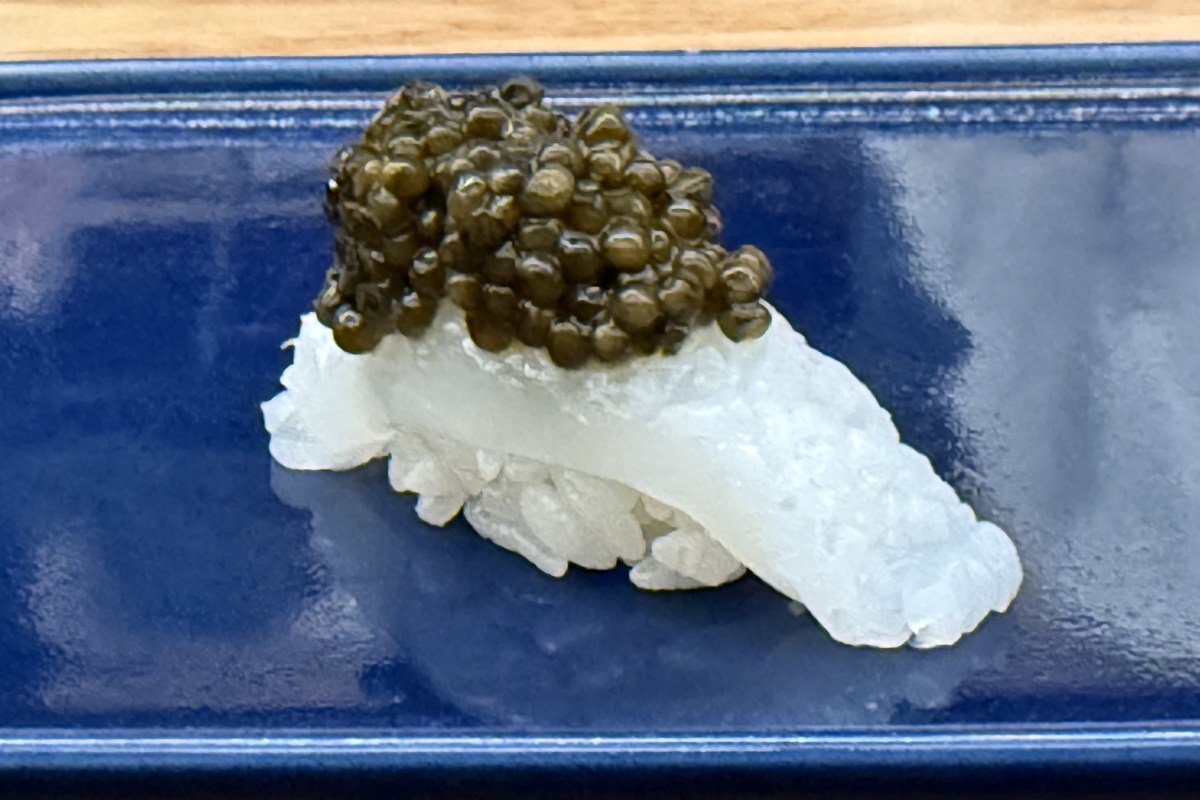 Nigiri sushi topped with squid and caviar on a blue ceramic plate