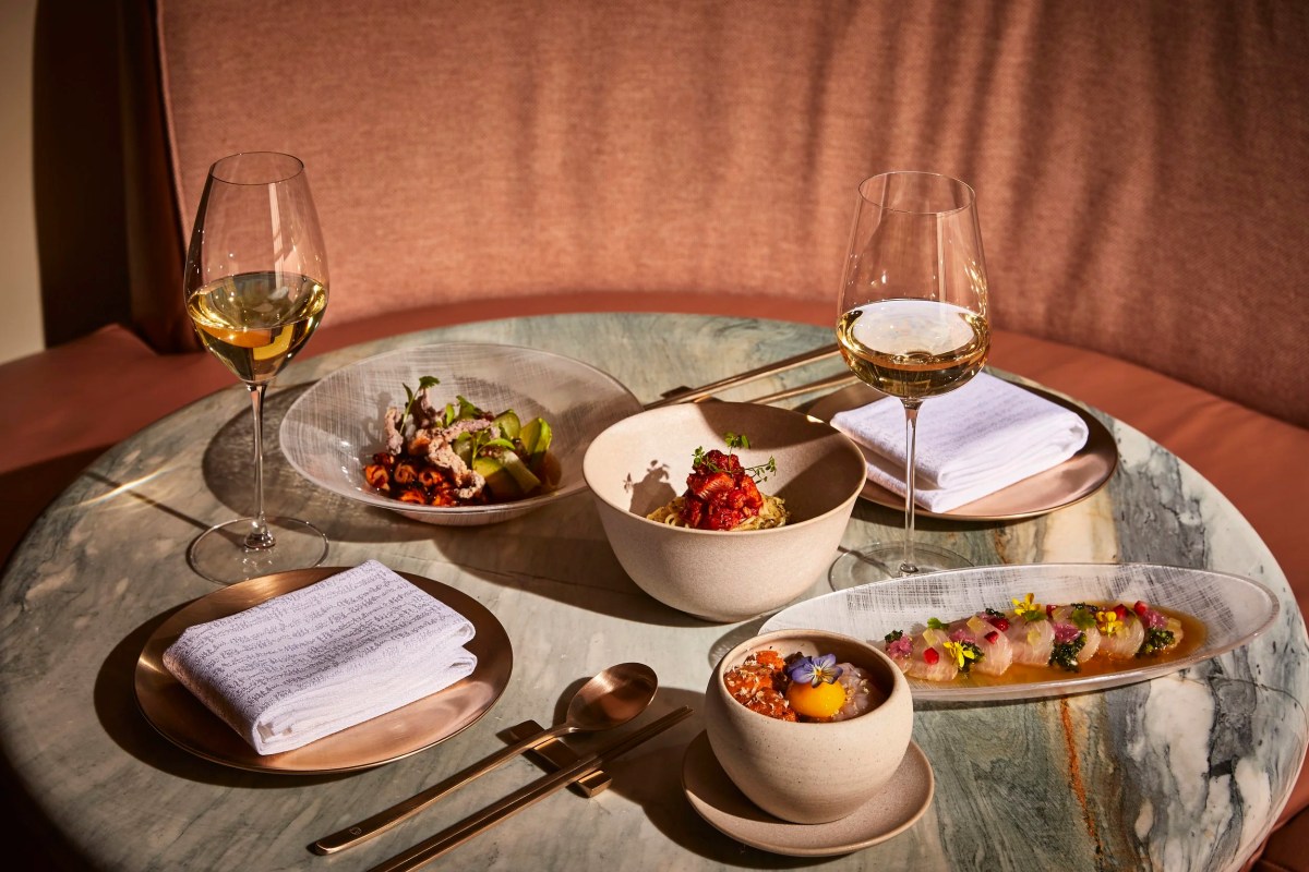 Marble table set with wine glasses and several small plates of Korean-inspired dishes
