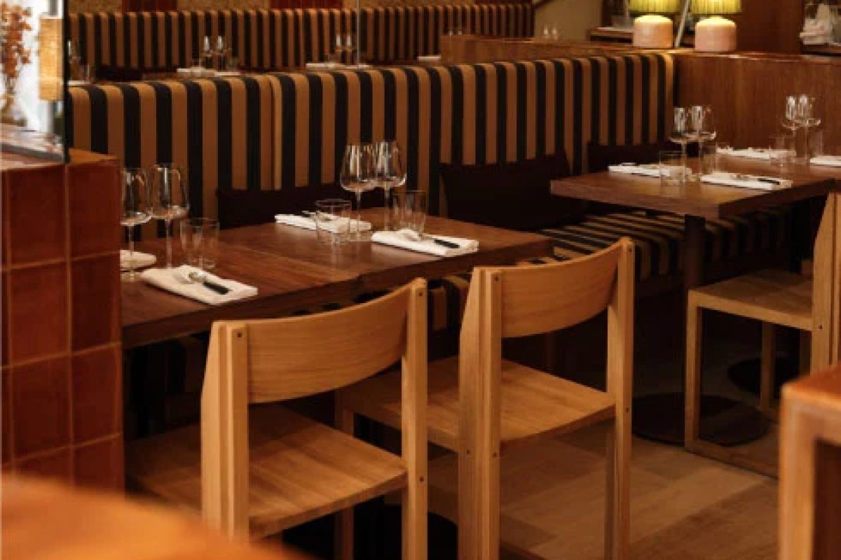 Restaurant dining room with striped booth seating, wooden tables set with glasses and cutlery