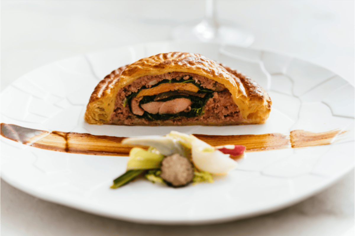 Elegant plated dish: pastry-wrapped terrine with foie gras and spinach, sauce drizzle, garnish