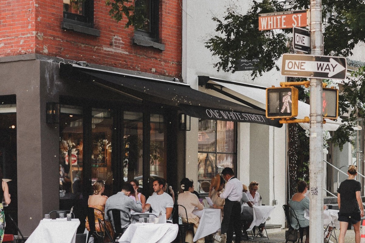 Exterior of One White Street restaurant with outdoor terrace tables, diners, and street sign reading White St