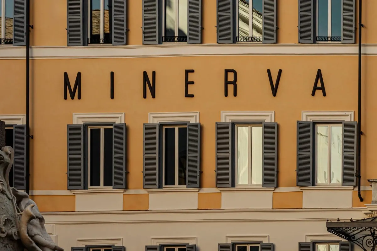 Close-up of the hotel's ochre façade with 'MINERVA' lettering and shuttered windows.