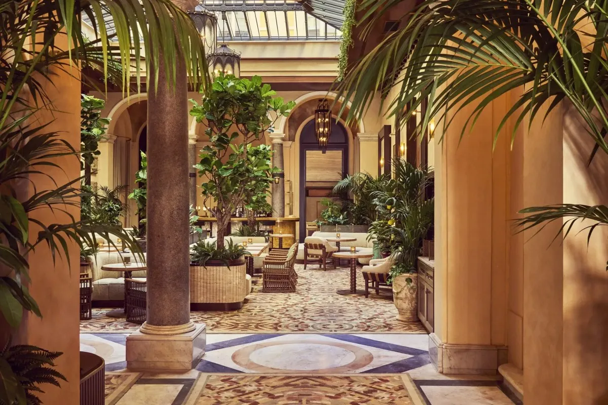 Elegant indoor courtyard lounge with palm trees, marble columns, patterned tile floor and seating