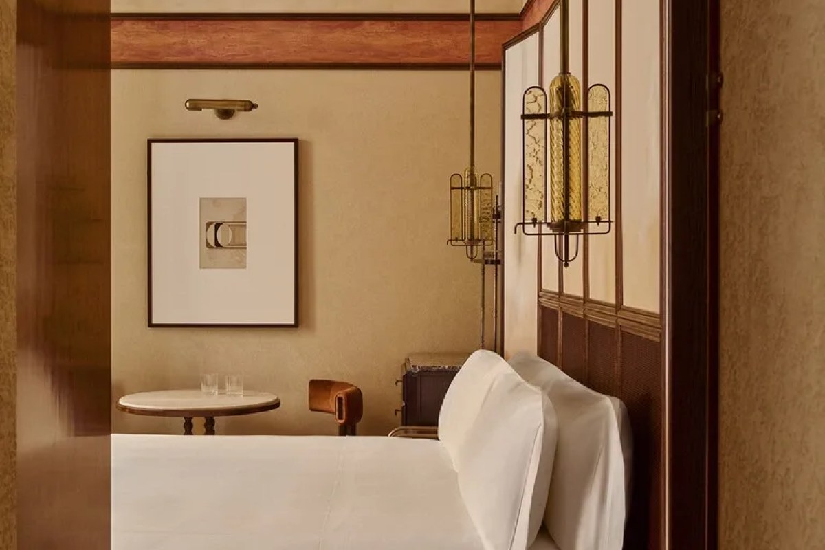 Guest room with white bedding, framed art, small round table and decorative glass pendant lights