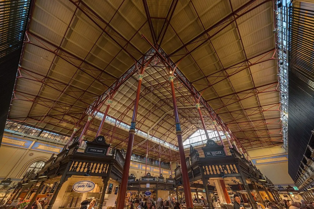 The cast-iron roof and timber trading stalls inside Östermalms Saluhall in Stockholm after the 2020 restoration