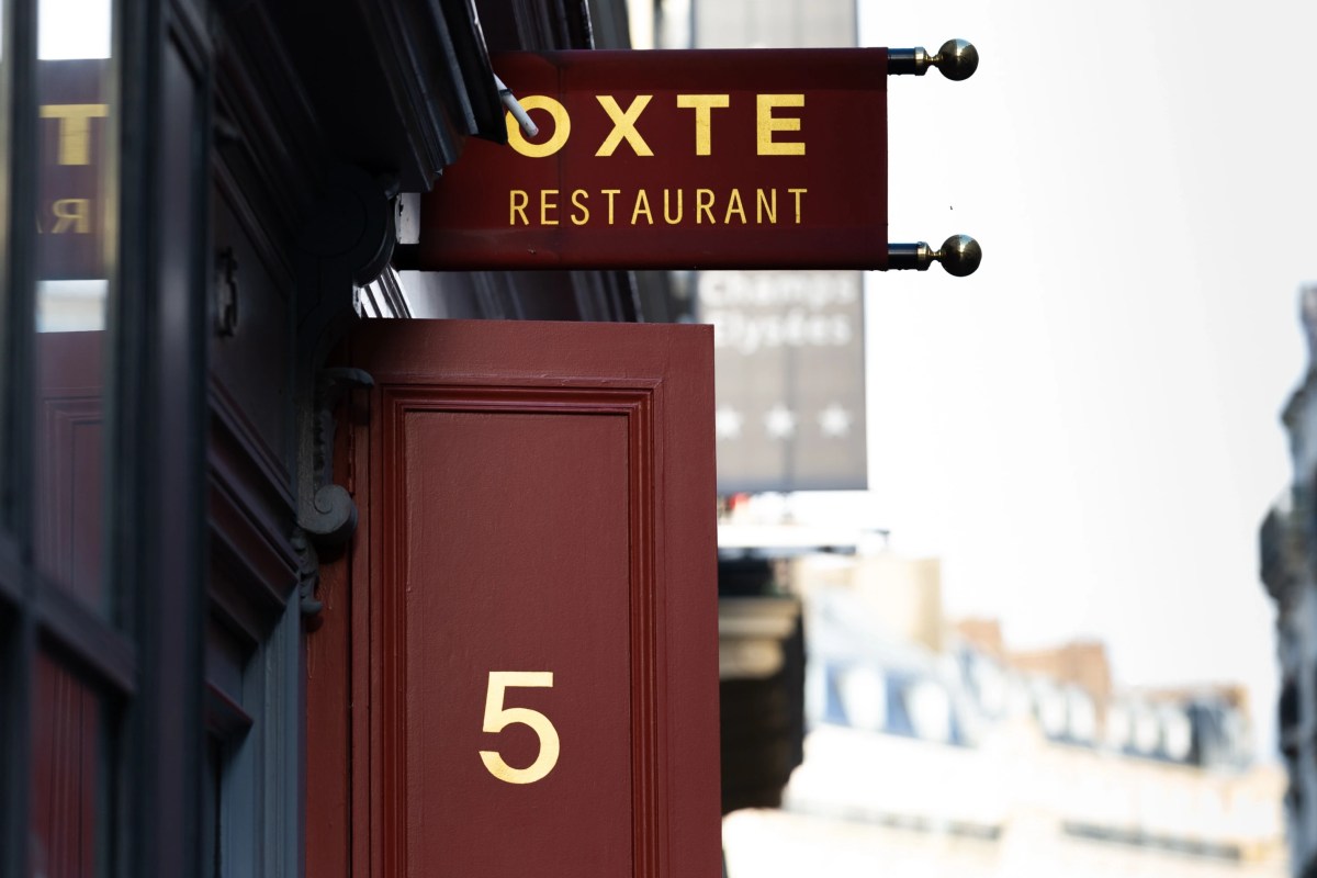 Exterior shop sign reading OXTE Restaurant above a red door numbered 5 on a Paris street