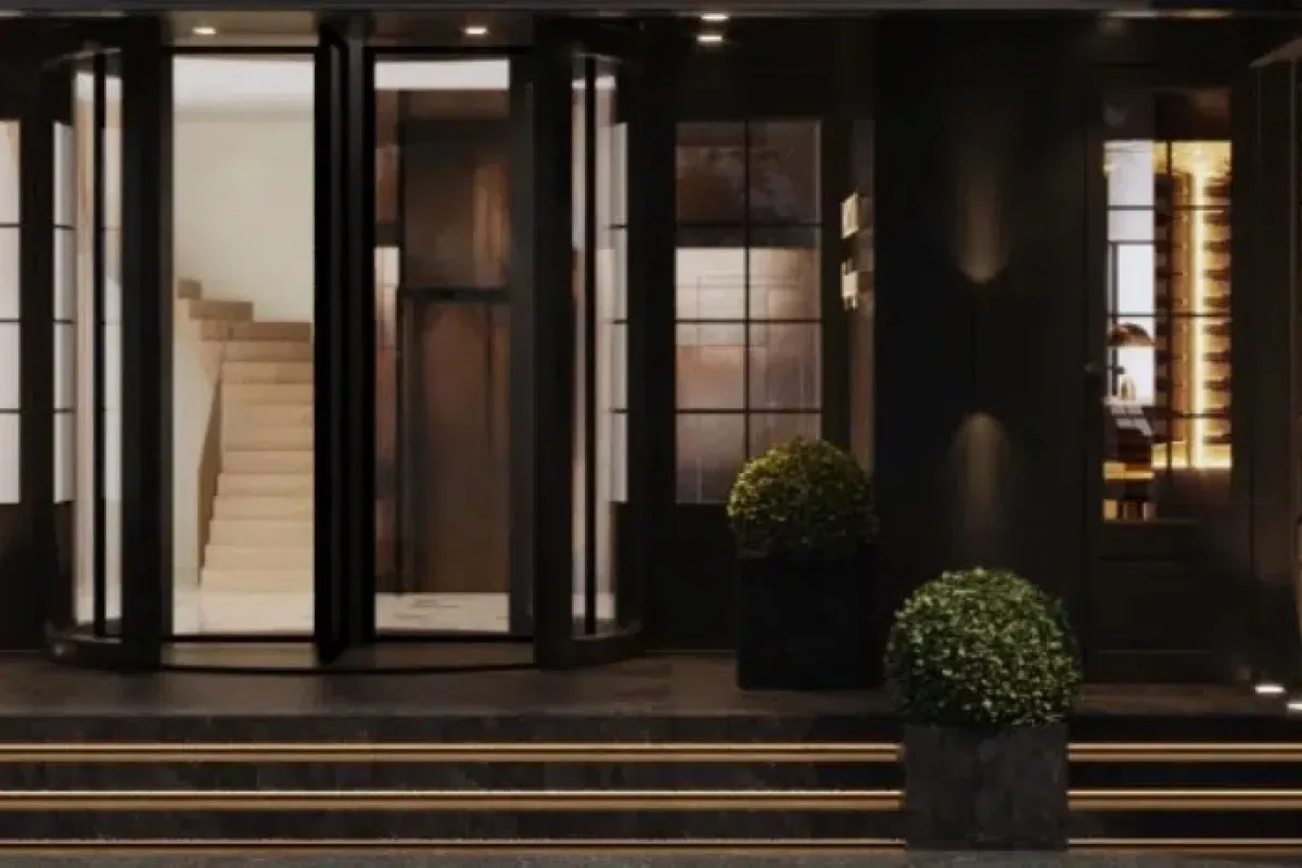 Close-up of the hotel's dark entrance with revolving door, staircase visible inside, and potted greenery
