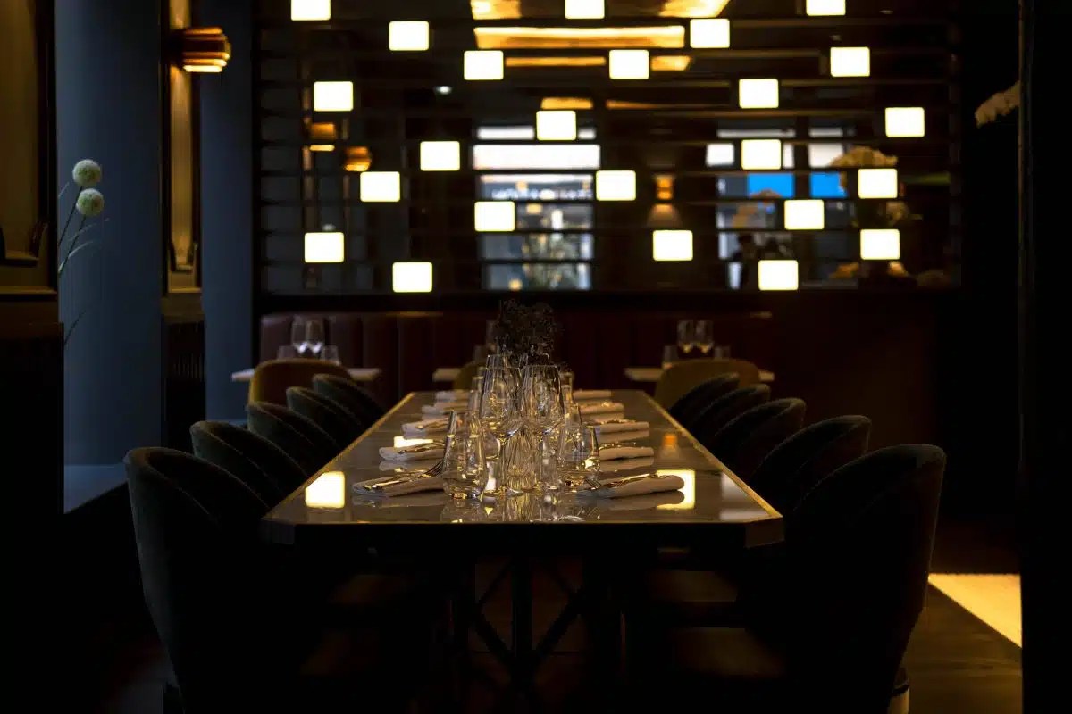 Stylish dining room with long table set for guests, backlit illuminated wall panel, and modern decor