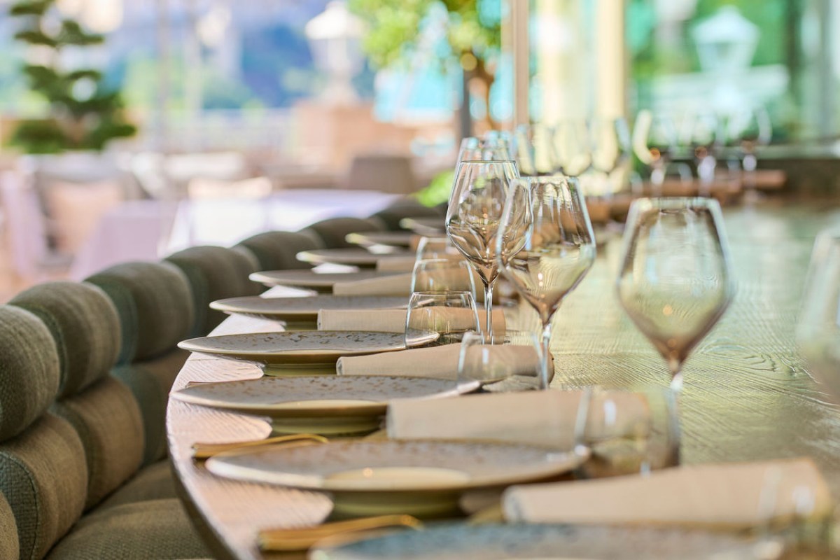 Elegant table setting with wine glasses and plates on a terrace overlooking greenery