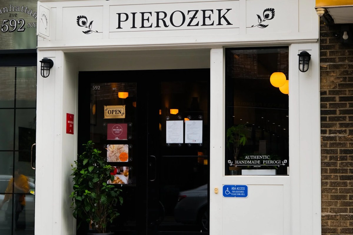 Exterior storefront of Pierozek restaurant with black sign and Michelin stickers on the door