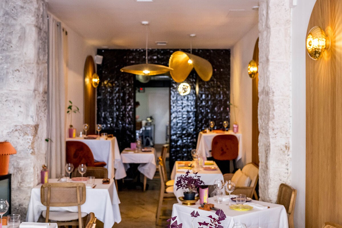 Dining room at Pirouette showing stone archways, gold sconces, brass pendant lights, and elegantly set tables