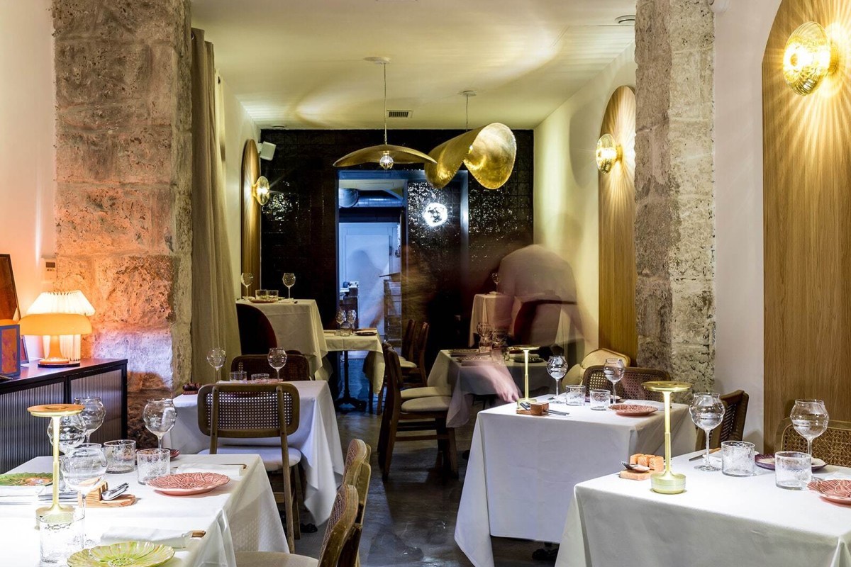 Interior dining room of Pirouette with stone pillars, gold pendant lights, and set tables with wine glasses