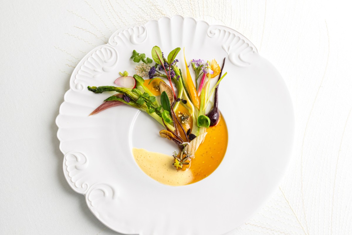Artfully plated vegetable dish with edible flowers on a white ornate plate