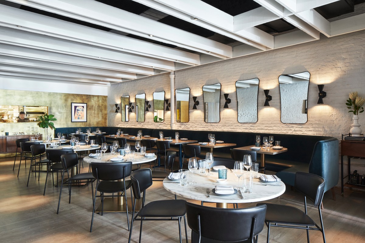 Dining room with marble tables, black chairs, teal banquette, and wall of mirrors